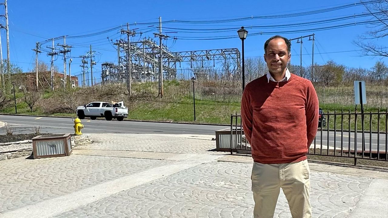 James Rather, director of strategic initiatives for the Southern Maine Planning and Development Commission, stands with a Central Maine Power substation in the background in Saco Monday. (Spectrum News/Sean Murphy)