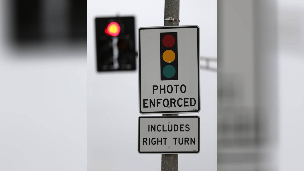 A sign warning of a photo-enforced red light camera hangs on a pole near an intersection Wednesday, Nov. 6, 2013, in St. Louis. (AP Photo/Jeff Roberson)