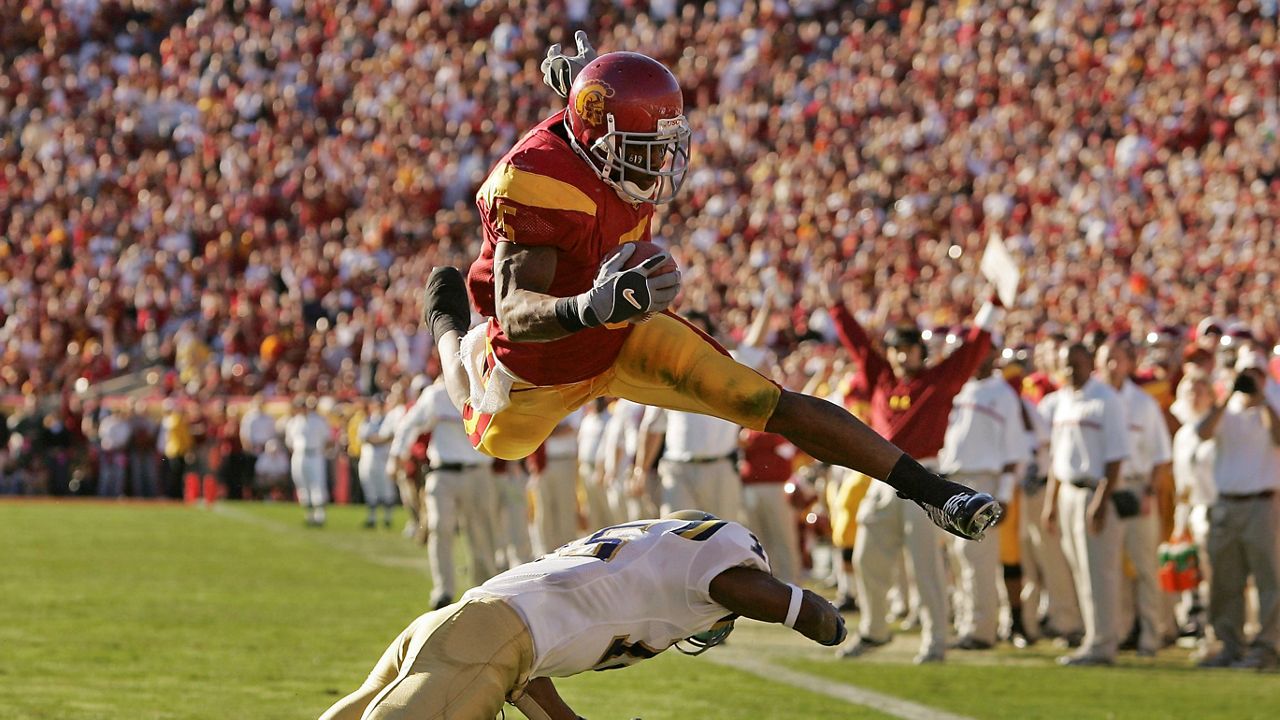 Southern California’s Reggie Bush leaps over UCLA defender Marcus Cassel as he rushes 13 yards for a touchdown in the second quarter of an NCAA college football game at the Los Angeles Memorial Coliseum on Dec. 3, 2005. (AP Photo/Chris Carlson)