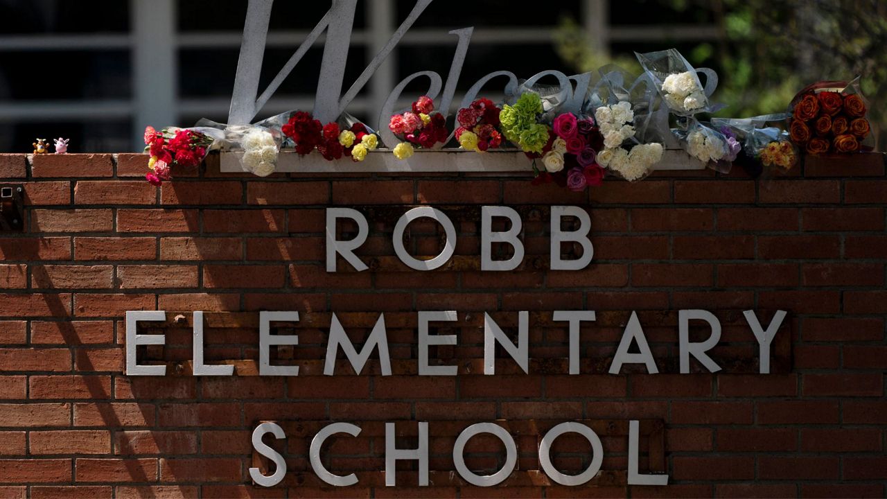 Flowers are placed around a welcome sign outside Robb Elementary School in Uvalde, Texas, Wednesday, May 25, 2022, to honor the victims killed in a shooting at the school. (AP Photo/Jae C. Hong)