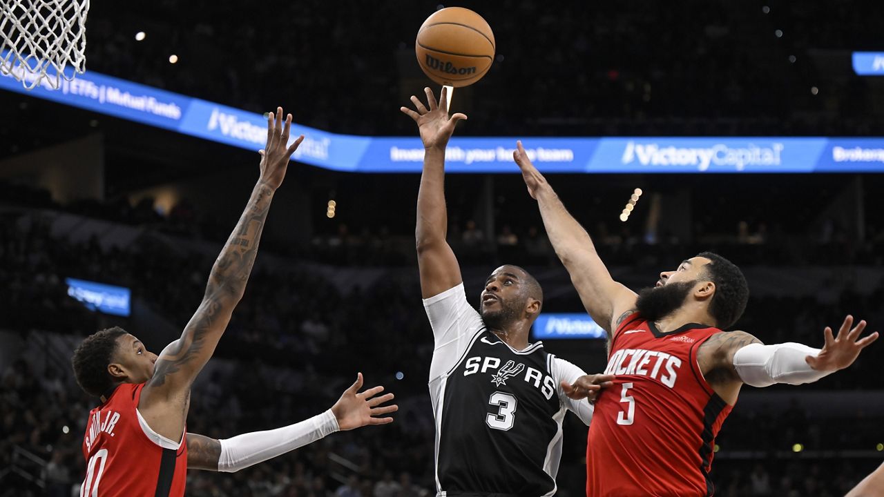 San Antonio Spurs' Chris Paul (3) goes to the basket against Houston Rockets' Fred Van Vleet (5) and Jabari Smith Jr., left, during the first half of an NBA basketball game, Monday, Oct. 28, 2024, in San Antonio. (AP Photo/Darren Abate)