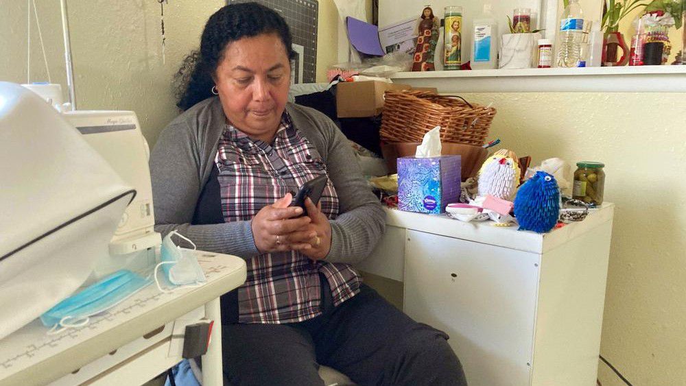 Rosalidia Dardon, 54, looks at a picture of her daughter in El Salvador as she sits in a refugee house in Texas, awaiting asylum or a protected immigration status on Nov. 4, 2021. At least seven statehouses have considered or left pending legislation this year to replace the term “illegal,” “alien,” or both from state laws referencing immigrants. Dardon knows from personal experience why the language surrounding immigration is so important. (Acacia Coronado/Report for America via AP)