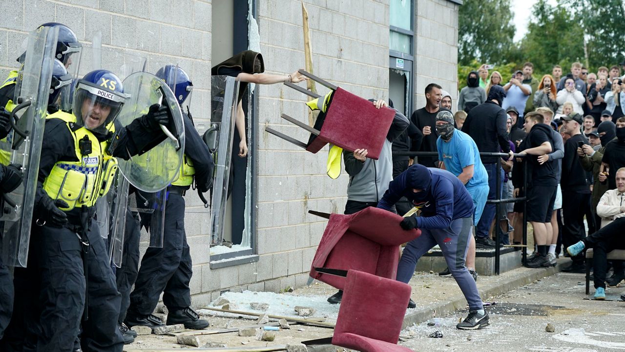 A chair is thrown at police officers as trouble flares during an anti-immigration protest outside the Holiday Inn Express in Rotherham, England, Sunday Aug. 4, 2024. (Danny Lawson/PA via AP)