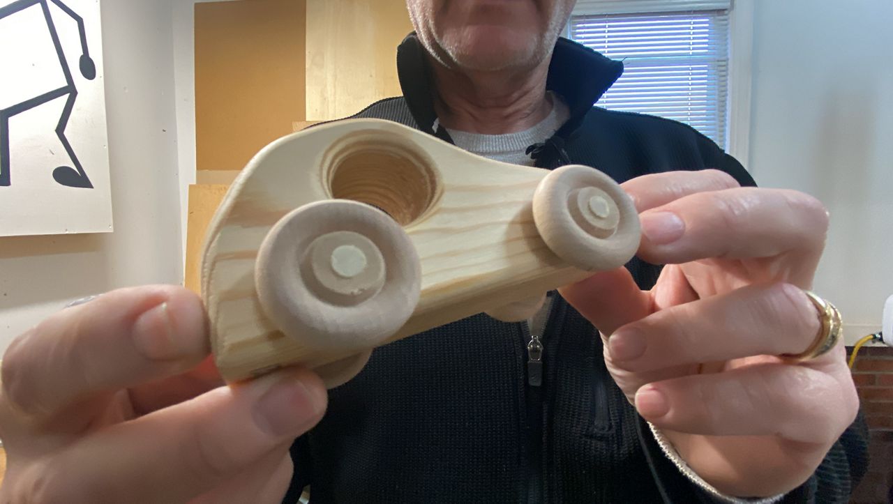 Roy Brookhart holds one of his wooden toy cars recently handcrafted in his garage.