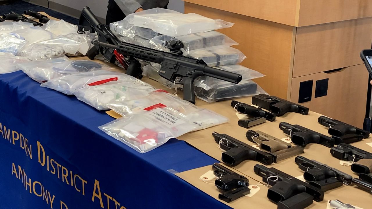 Firearms and drugs sit on a table at the Hampden County District Attorney's Office on Tuesday. (Spectrum News 1/Devin Bates)