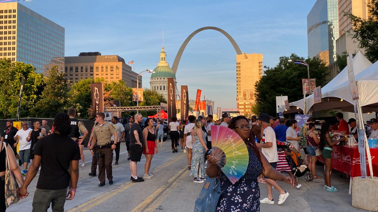 People fan themselves to stay cool during a hot summer evening near the St. Louis Arch. 