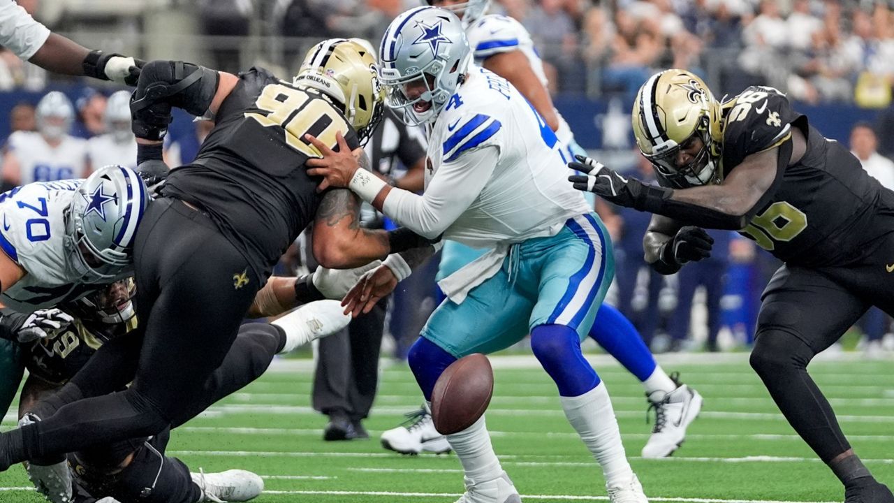 Dallas Cowboys quarterback Dak Prescott, center, fumbles the ball while being pressured by New Orleans Saints defensive tackle Bryan Bresee (90) and defensive end Carl Granderson (96) during the second half of an NFL football game, Sunday, Sept. 15, 2024, in Arlington, Texas. (AP Photo/Tony Gutierrez)