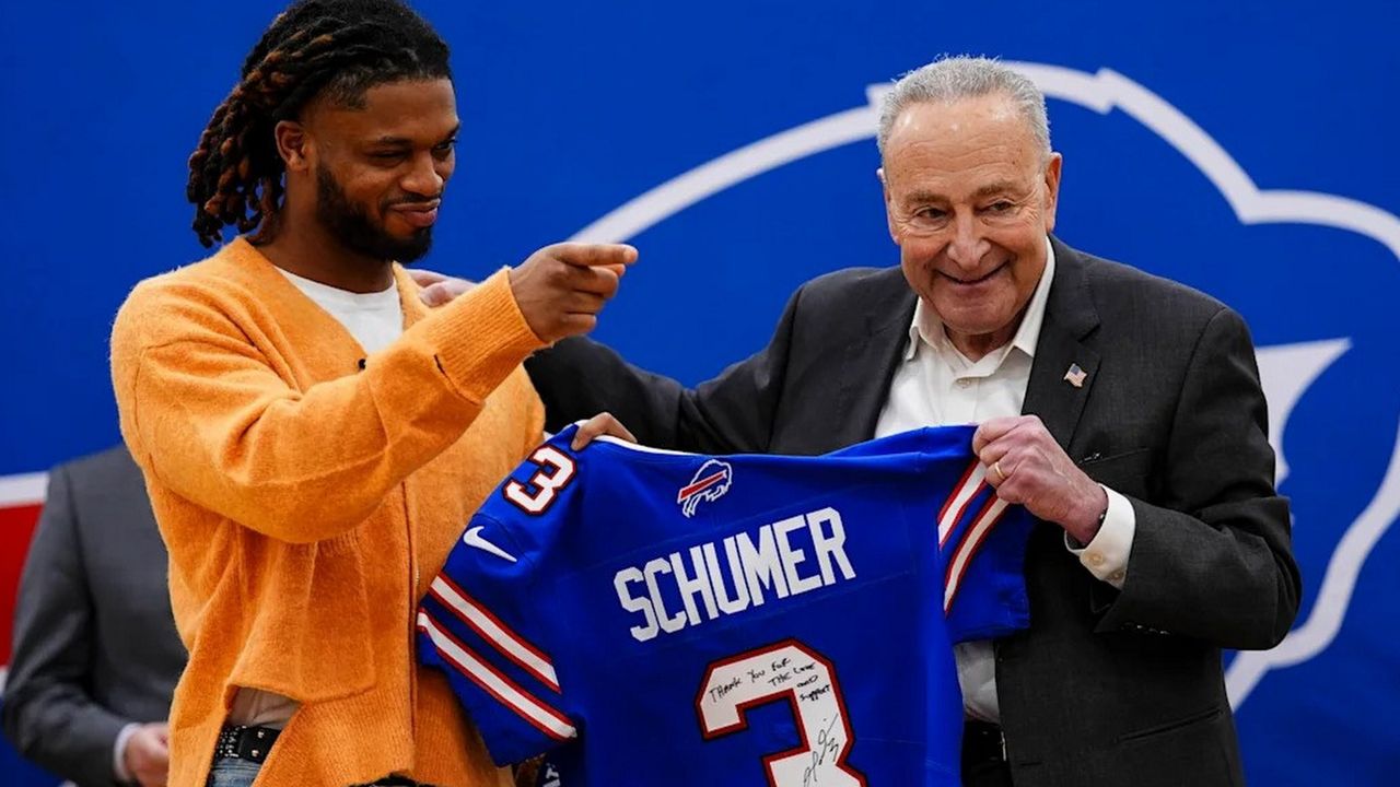 damar hamlin and chuck schumer hold up a blue buffalo bills jersey with schumer's name and the number 3 on the back