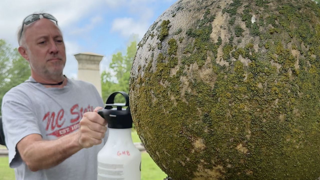 A Volunteer spraying cleaner on a grave marker.