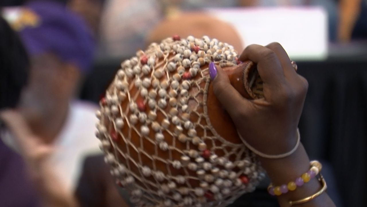 A member of the audience shakes this African instrument at the kick off of the festival.