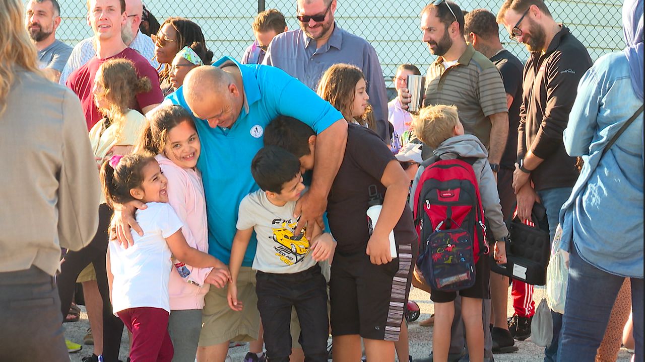 A father embraces his children outside of Harrison Elementary School after reciting 11 pledges to be involved in their school lives (Spectrum News/ Tanya Velazquez)