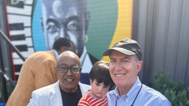 Peabo Bryson standing infront of a mural in his honor with another man and child (X / City of Greenville)