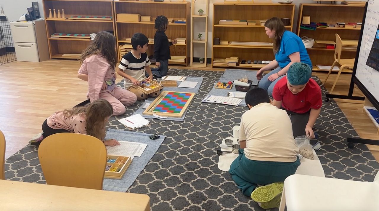 children on rug in school, working on school projects