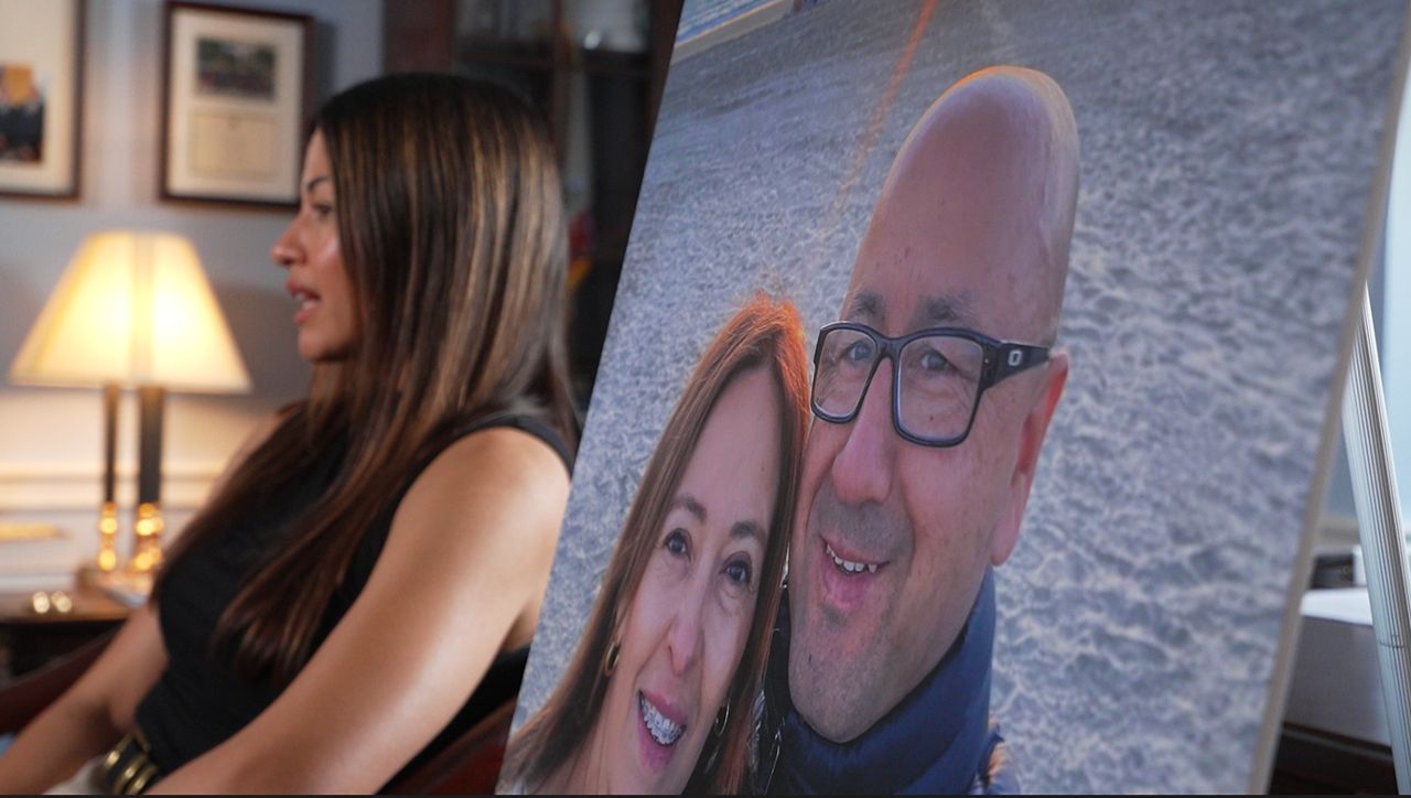 Stephanie Gonzalez speaks to Spectrum News alongside a photo of her parents, Gladys and Nelson. The couple, who lived in California for over 30 years, were deported in March after a routine check-in with Immigration and Customs Enforcement. (Spectrum News/KJ Carrick)