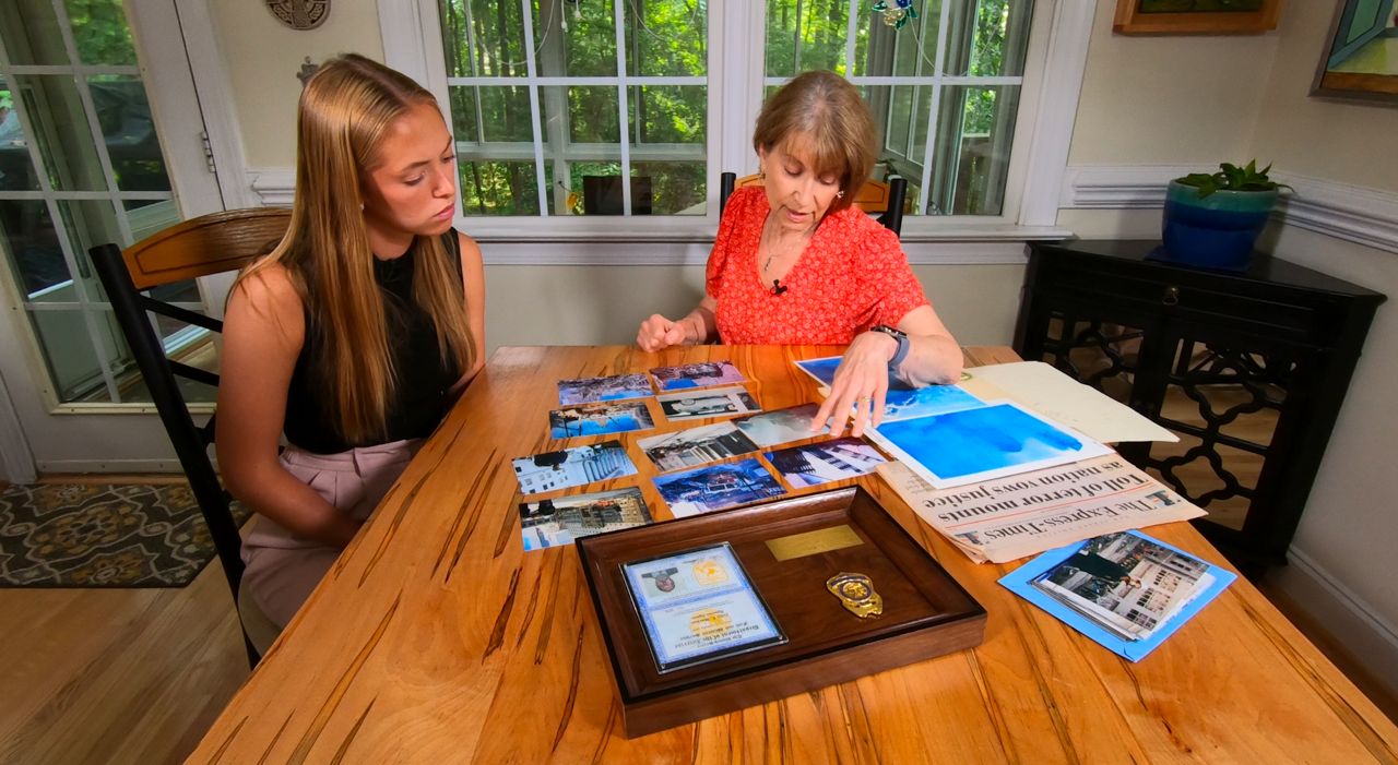 Lorraine Meehan, right, looks at images her late husband took while working recovery and cleanup at Ground Zero in New York City. (Spectrum News 1/Mark Barger)