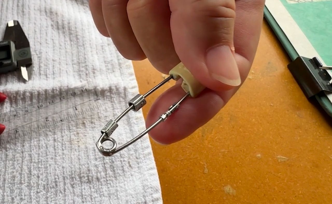 Susan Campbell holding a safety pin with bird bands. (Spectrum News 1/John Stampf)