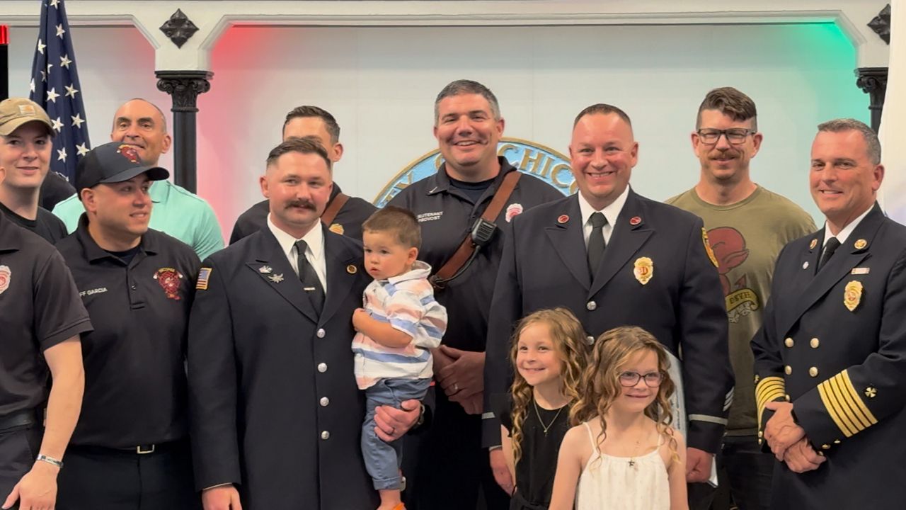 Nicholas Brown and Gregory Pray pose for a photo with family and colleagues after being promoted within the Chicopee Fire Department. (Spectrum News 1/Devin Bates)