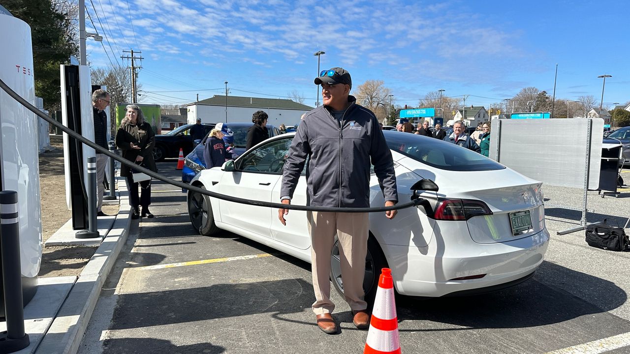 Federal Highway Administrator Shailen Bhatt demonstrates how to use one of the new charging stations at the Rockland Hannaford on Tuesday. (Spectrum News/Susan Cover)