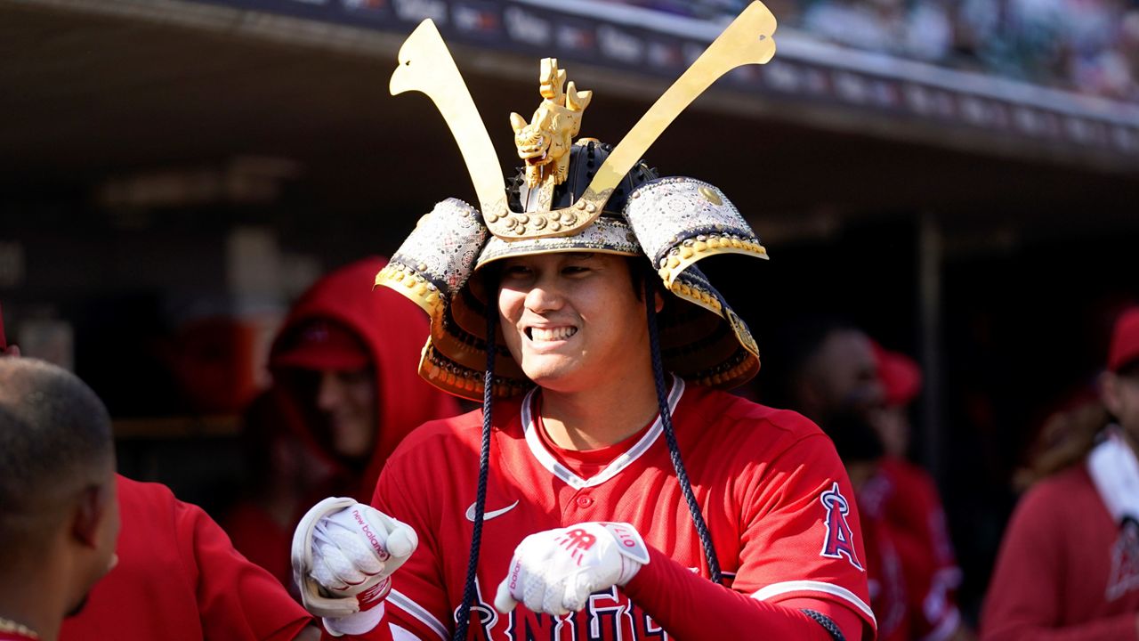 Shohei Ohtani of the Los Angeles Angels celebrates wearing a samurai  warrior helmet in the dugout after hitting a two-run home run in the third  inning of a baseball game against the