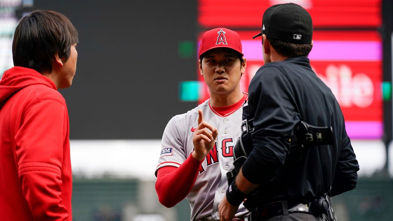 Los Angeles Angels starting pitcher Shohei Ohtani talks with home plate umpire Pat Hoberg after the first inning of a baseball game, in which he was called for a pitch clock violation against the Seattle Mariners, Wednesday, April 5, 2023, in Seattle. (AP Photo/Lindsey Wasson)