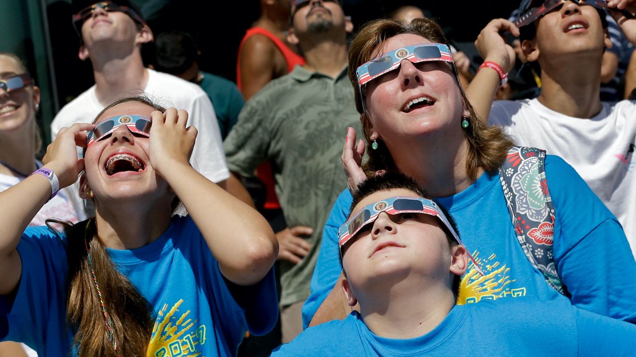 Michelle Picantine, right, watches a phase of a partial solar eclipse with her children Emily, 15, left, and Jake, 11, at the Orlando Science Center, Monday, Aug. 21, 2017, in Orlando, Fla. (AP Photo/John Raoux)