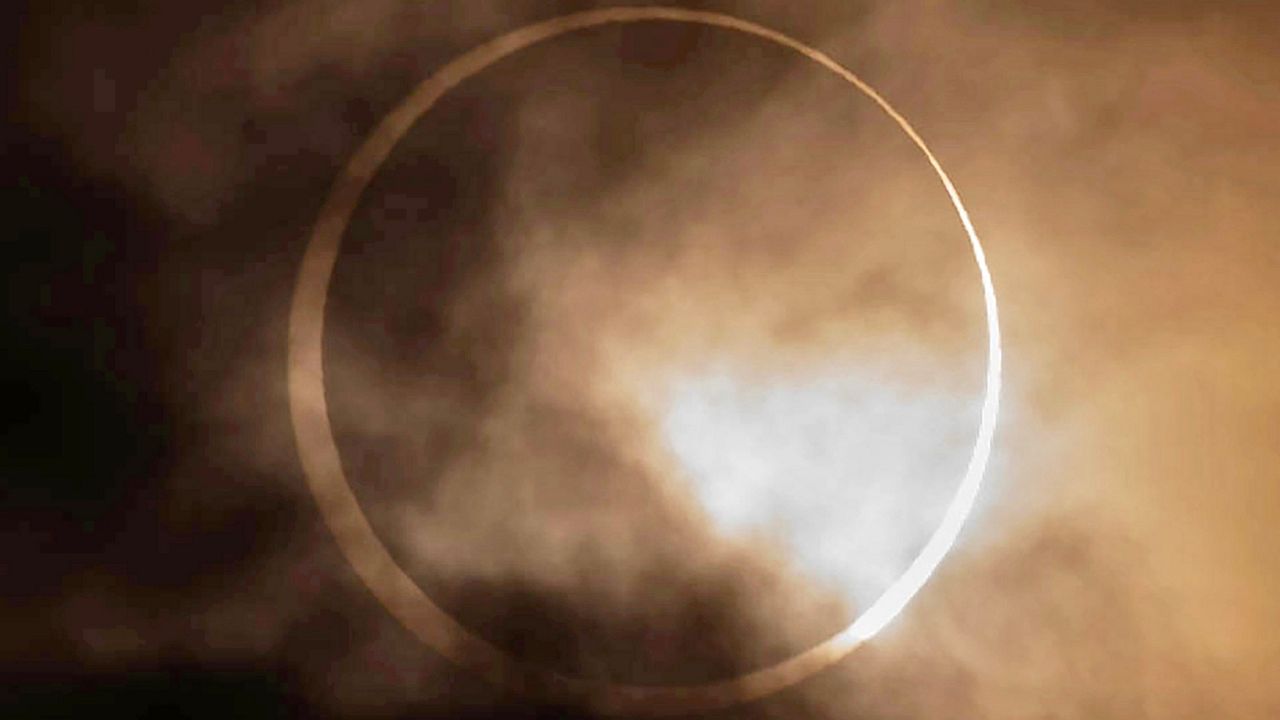 The annular solar eclipse appears from behind clouds above Skinner Butte in Eugene, Ore. Saturday, Oct. 14, 2023. (Chris Pietsch/The Register-Guard via AP)