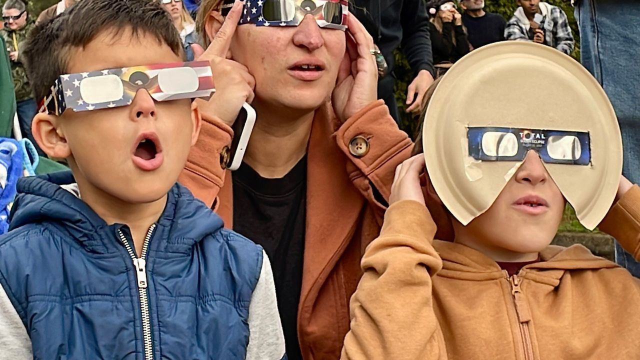Samia Harboe, her son Logan and her friend's son wear eclipse glasses during totality of the annular solar eclipse in Eugene, Ore., on Saturday, Oct. 14, 2023. 