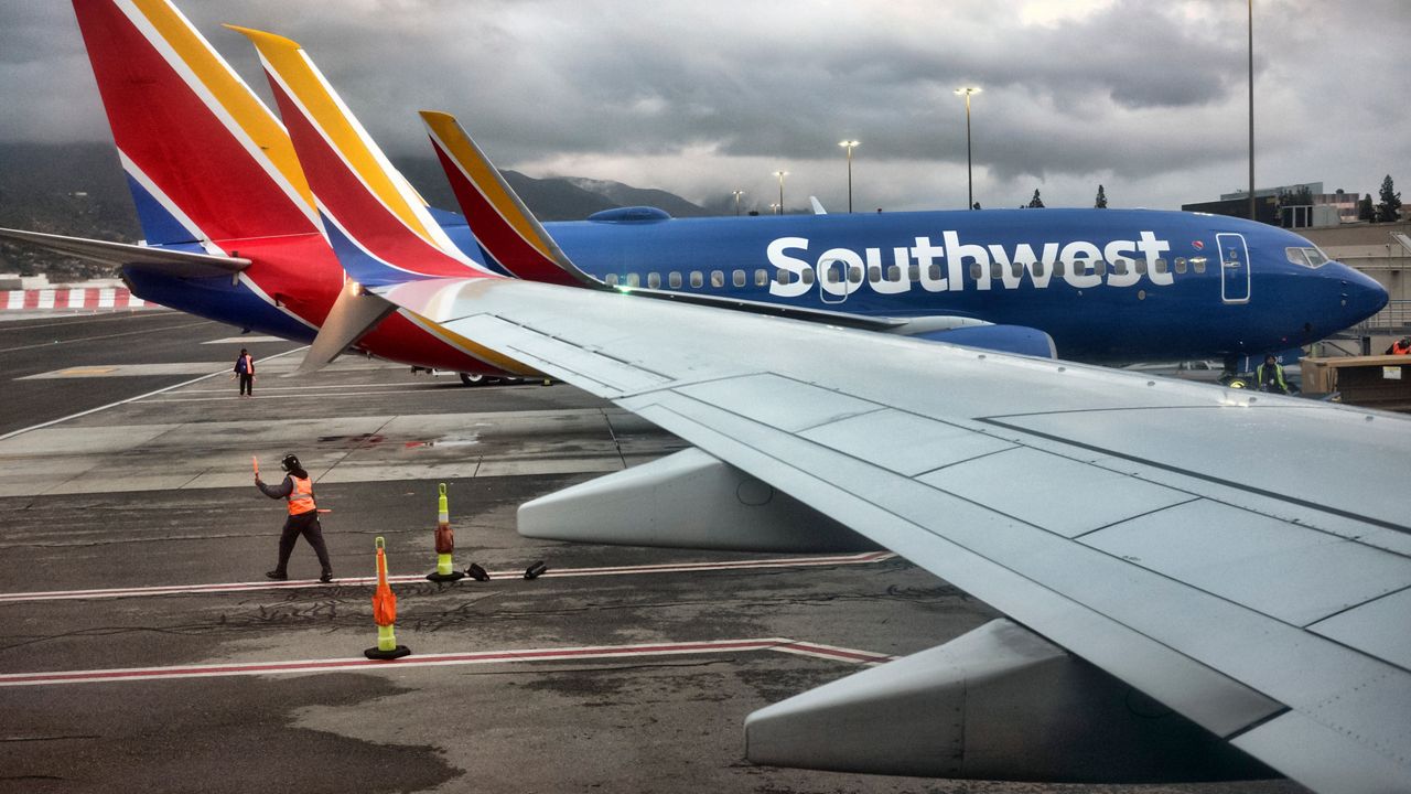 A Southwest Airlines ground crew directs a plane out of the terminal at Hollywood Burbank Airport in Burbank, Calif. (AP Photo/Richard Vogel)