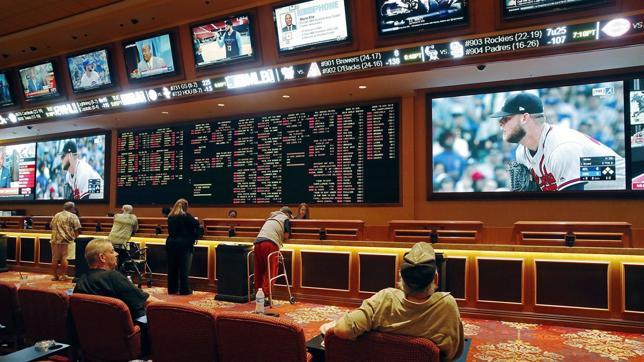 In this May 14, 2018, file photo, people make bets in the sports book at the South Point hotel and casino in Las Vegas. (AP Photo/John Locher)