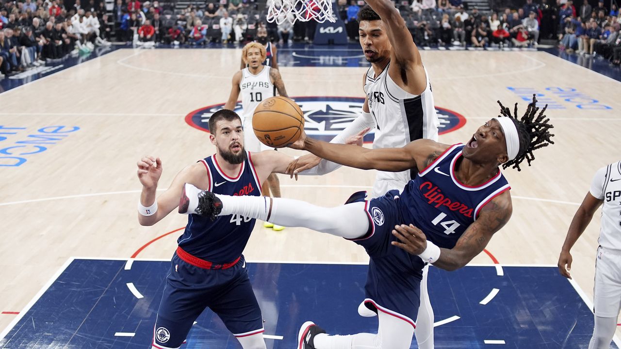 Los Angeles Clippers guard Terance Mann, right, shoots as San Antonio Spurs center Victor Wembanyama, top, defends and center Ivica Zubac watches during the first half of an NBA basketball game, Monday, Nov. 4, 2024, in Inglewood, Calif. (AP Photo/Mark J. Terrill)