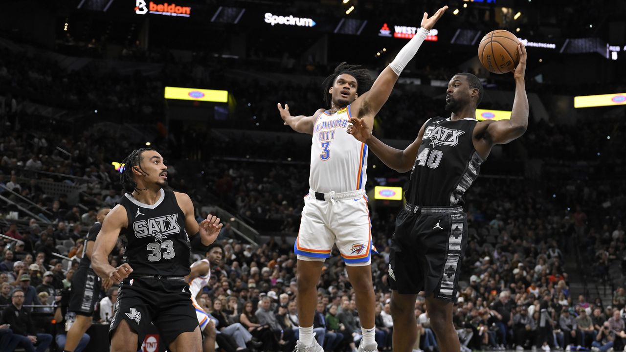 Oklahoma City Thunder's Dillon Jones (3) tangles with San Antonio Spurs' Harrison Barnes (40) and Tre Jones during the first half of an Emirates NBA Cup basketball game, Tuesday, Nov. 19, 2024, in San Antonio. (AP Photo/Darren Abate)