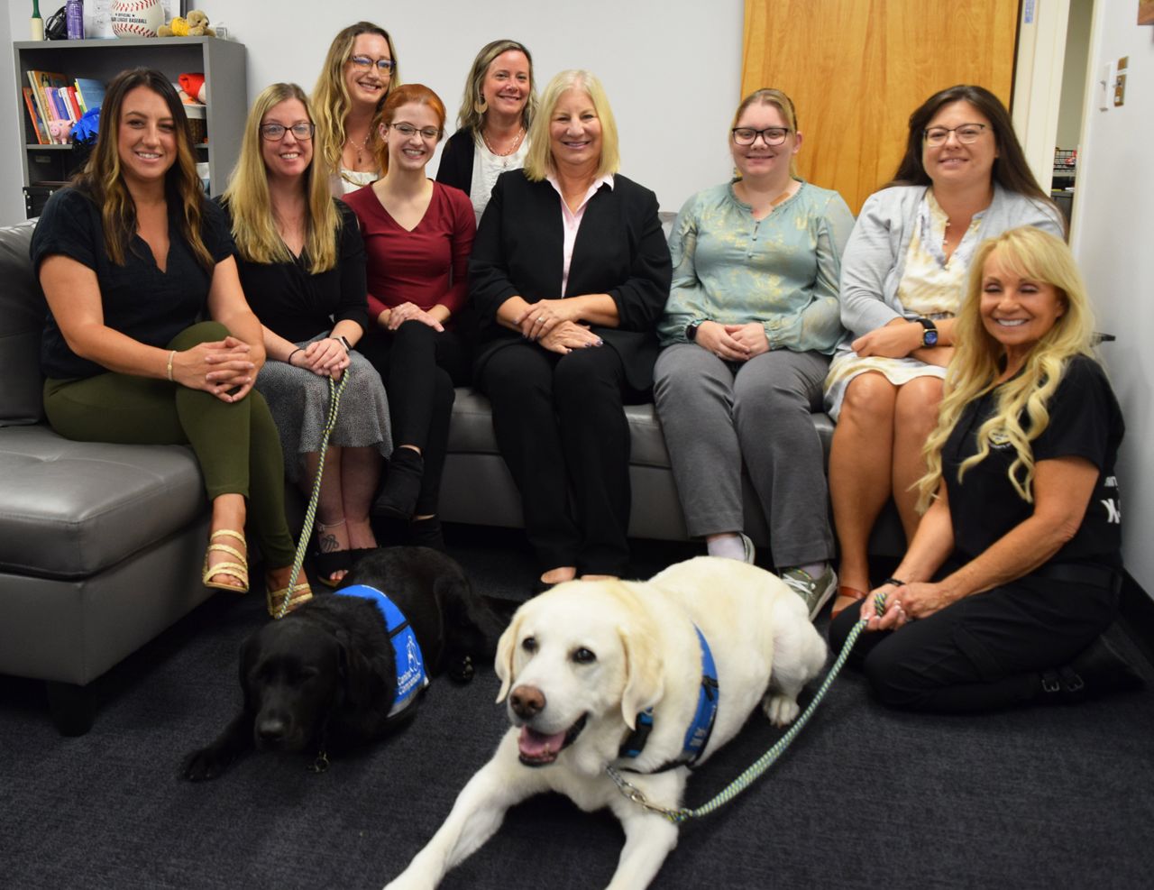 a group of seated women with two large dogs