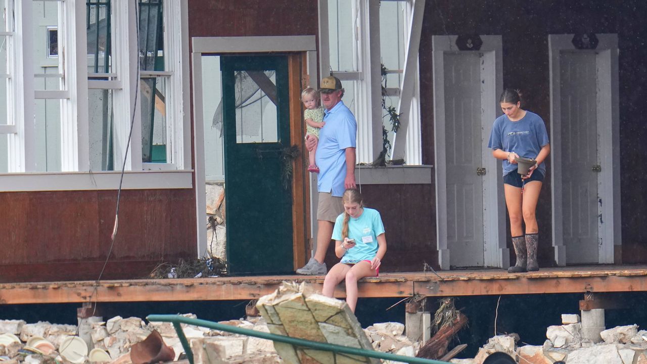 A person salvages a bell from the main building at Camp Mystic along the banks of the Guadalupe River after a flash flood swept through the area Sunday, July 6, 2025, in Hunt, Texas. (AP Photo/Julio Cortez)