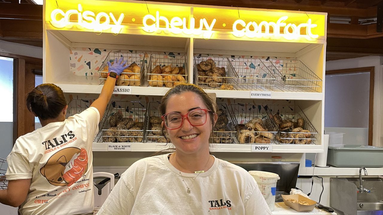 Talia Bongolan-Schwartz, who is the co-founder of Tali's Bagels & Schmear, working behind the counter at the bagel shop's new location in Ward Village. Kelly Bongolan-Schwartz, Talia's wife and co-founder of the bagel business, was busy making bagels. (Spectrum News/Michelle Broder Van Dyke)