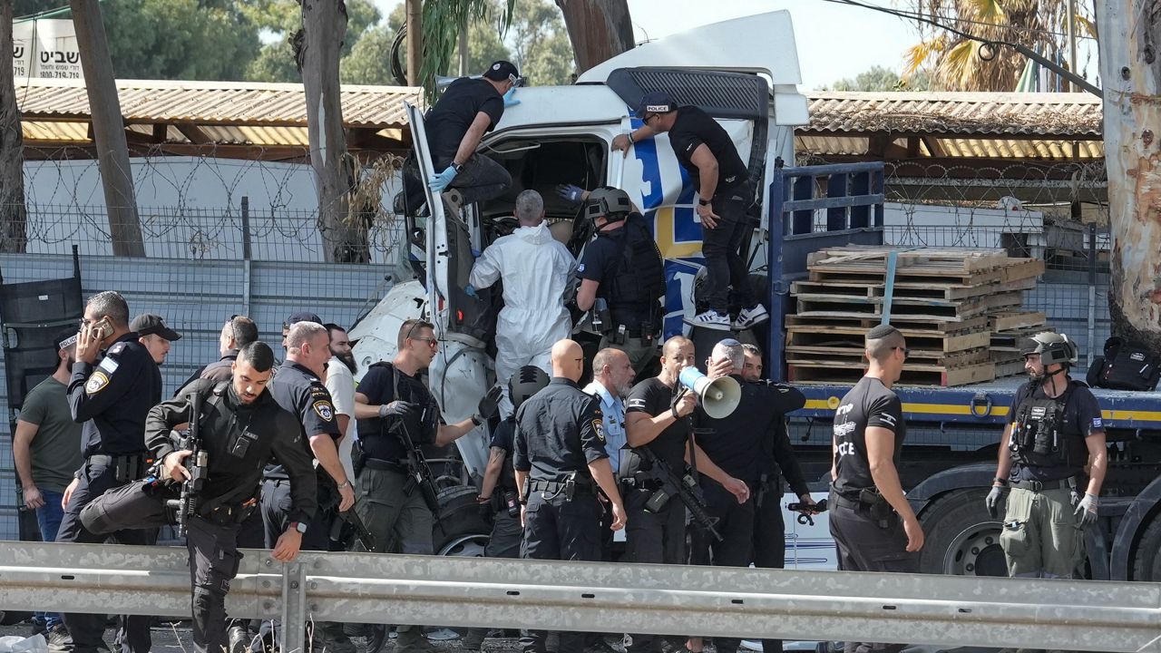 Israeli police climb on a truck that rammed into a bus stop near the headquarters of Israel's Mossad spy agency, wounding dozens of people, according to Israel's Magen David Adom rescue service in Tel Aviv, Israel, Sunday, Oct. 27, 2024. (AP Photo/Oded Balilty)