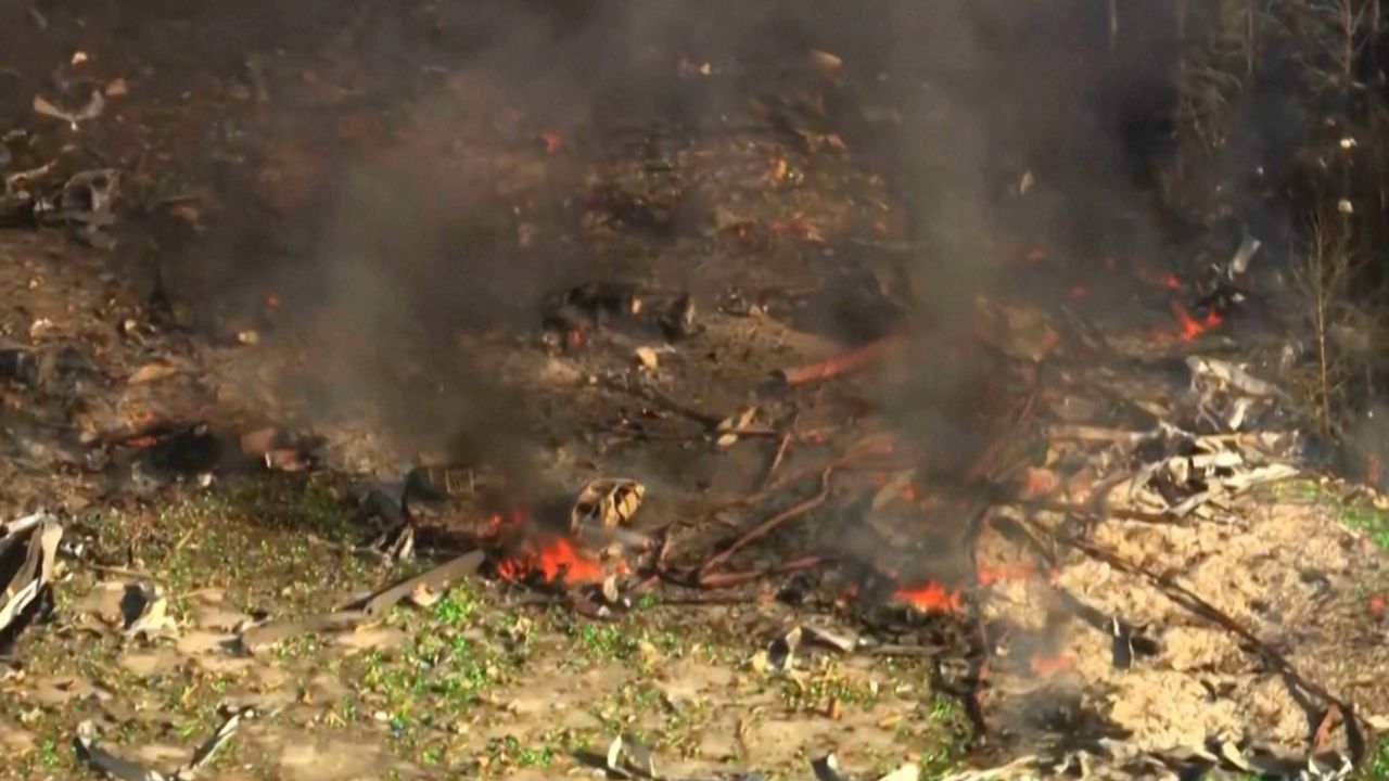 Smoke fills the air as debris covers the ground and vehicles after a powerful blast ripped through a military explosives manufacturing plant in Hickman County, Tenn., on Friday, Oct. 10, 2025.   (WTVF-TV via AP)