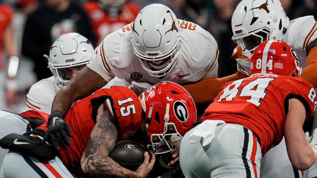 Georgia quarterback Carson Beck (15) runs into Texas defensive lineman Vernon Broughton (45) during the first half of the Southeastern Conference championship NCAA college football game, Saturday, Dec. 7, 2024, in Atlanta. (AP Photo/Mike Stewart)