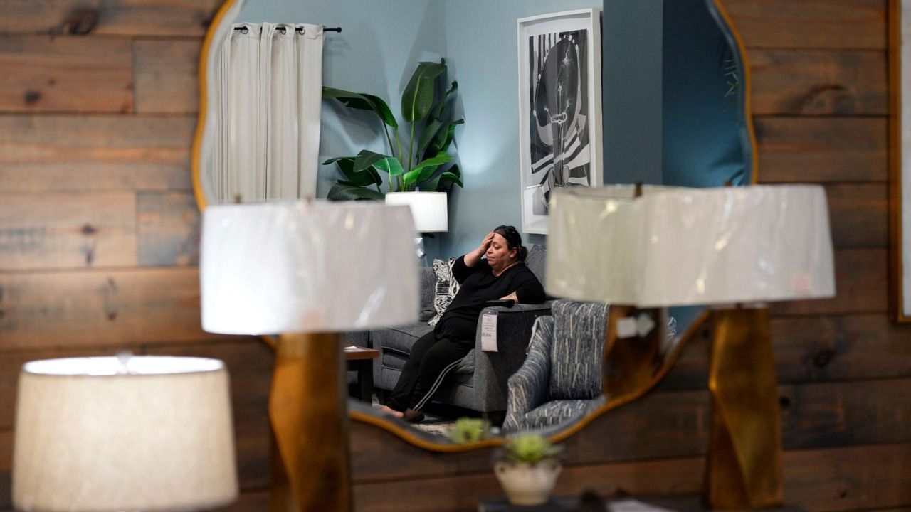 Houston resident Adriana Guerrero is reflected in a mirror as she spend time at Gallery Furniture, which is being used as a temporary shelter, to cool off and and have a meal, Tuesday, July 9, 2024, in Houston. The effects of Hurricane Beryl left most in the area without power. (AP Photo/Eric Gay)