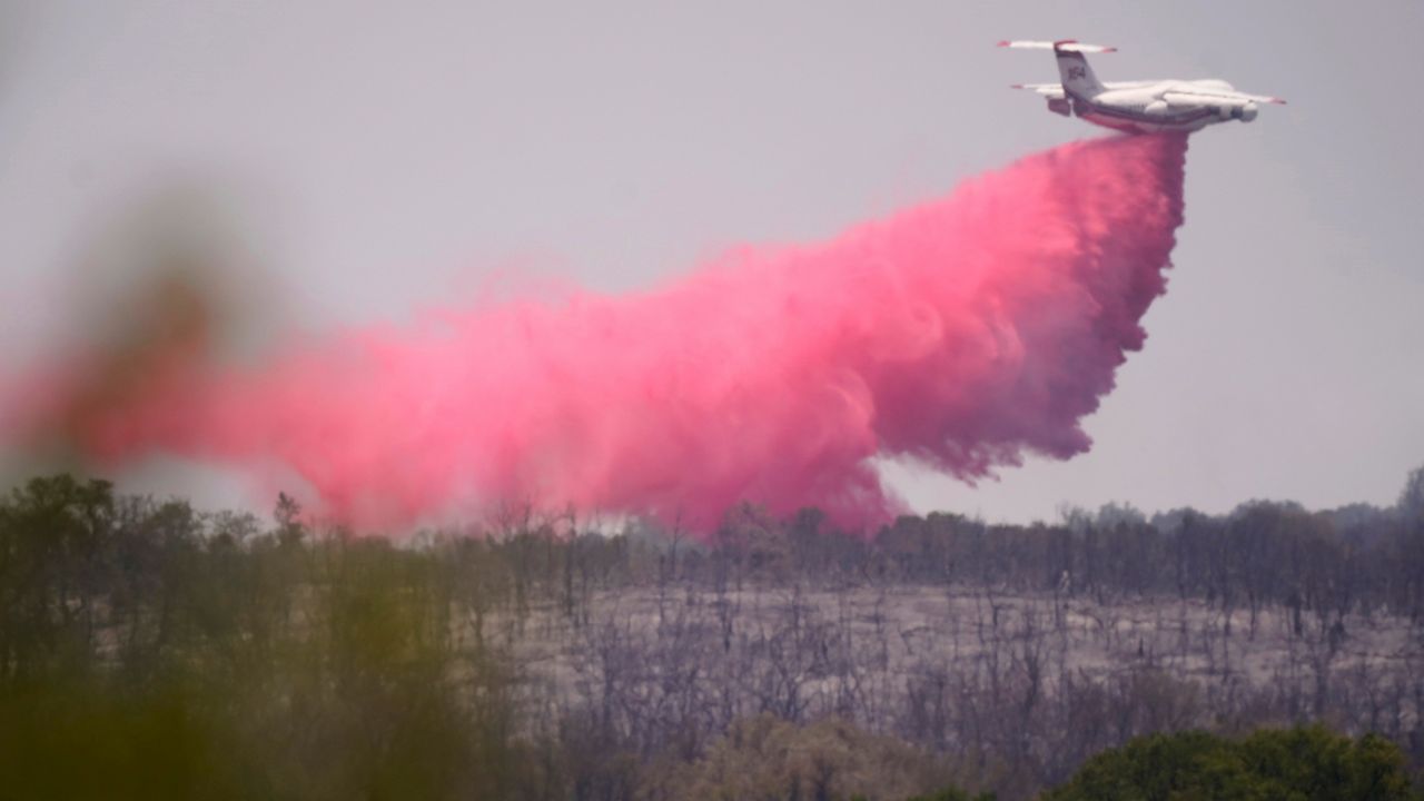 An airplane drops fire retardant on a wildfire near Glen Rose, Texas, Wednesday, July 20, 2022. (AP Photo/LM Otero)