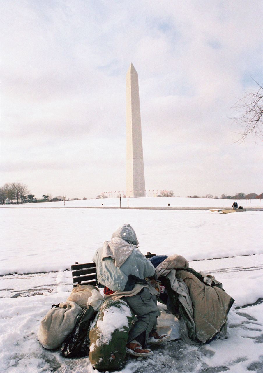 An unidentified street person huddles with his belongings on the Ellipse in morning on Thursday, Nov. 23, 1989 in Washington Monument after a light snow hit the area late Wednesday night. Some 4-inches of snow hit the Washington area on this Thanksgiving Day. (AP Photo/Ron Edmonds)