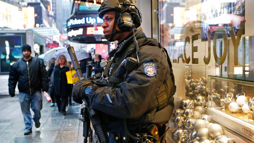  Un policía fuertemente armado se refugia bajo un alero sobre una tienda en Times Square. Archivo