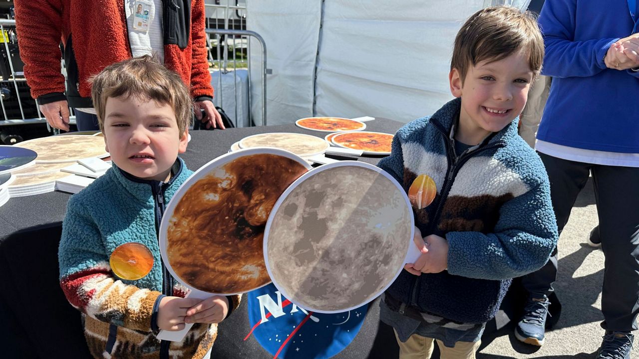 Gabriel Kauffman, 4, and his brother, Theodore, 6, demonstrate a total solar eclipse at a NASA booth at the Great Lakes Science Center in Cleveland, on Sunday, April 7, 2024. They live in Baltimore and came to the Cleveland area to see the eclipse with relatives. (AP Photo/Stephanie Nano)