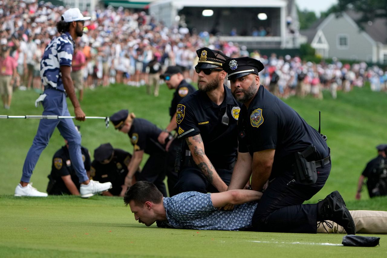 Six intruders run onto 18th green and spray powder, delaying finish of
