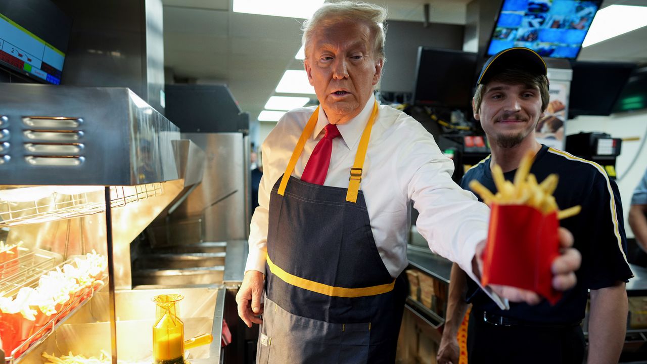 Republican presidential nominee former President Donald Trump, left, hands off an order of fries after working alongside an employee during a visit to McDonald's in Feasterville-Trevose, Pa., Sunday, Oct. 20, 2024. (Doug Mills/The New York Times via AP, Pool)