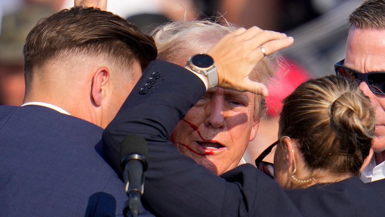 Republican presidential candidate former President Donald Trump is helped off the stage by U.S. Secret Service agents at a campaign event in Butler, Pa., on Saturday, July 13, 2024. (AP Photo/Gene J. Puskar)