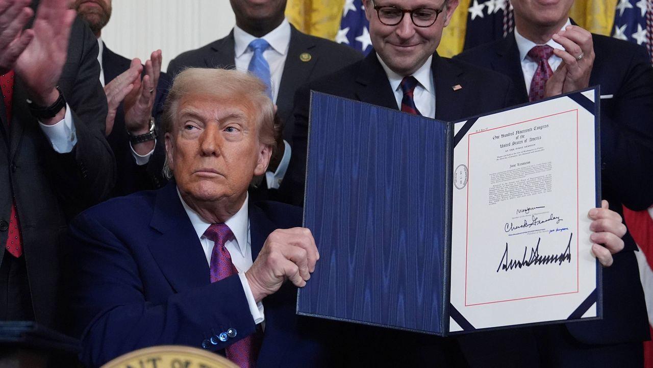 President Donald Trump holds up a signed bill blocking California's rule banning the sale of new gas-powered cars by 2035 in the East Room of the White House, Thursday, June 12, 2025, in Washington. (AP Photo/Evan Vucci)