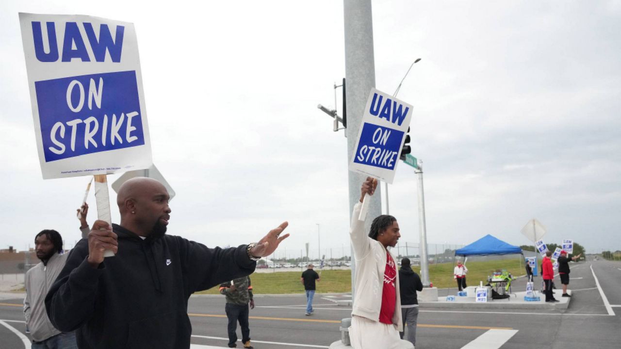 Striking United Auto Workers hold their signs as passing cars honk in front of the General Motors Wentzville Assembly Plant in Wentzville, Missouri on Saturday, Septe