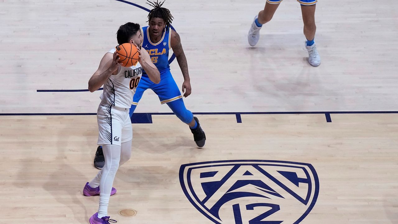 A Pac-12 logo is shown on the floor of Haas Pavilion as California forward Fardaws Aimaq (00) looks to pass while being defended by UCLA guard Brandon Williams during an NCAA college basketball game in Berkeley, Calif., Feb. 10, 2024. (AP Photo/Jeff Chiu, File)