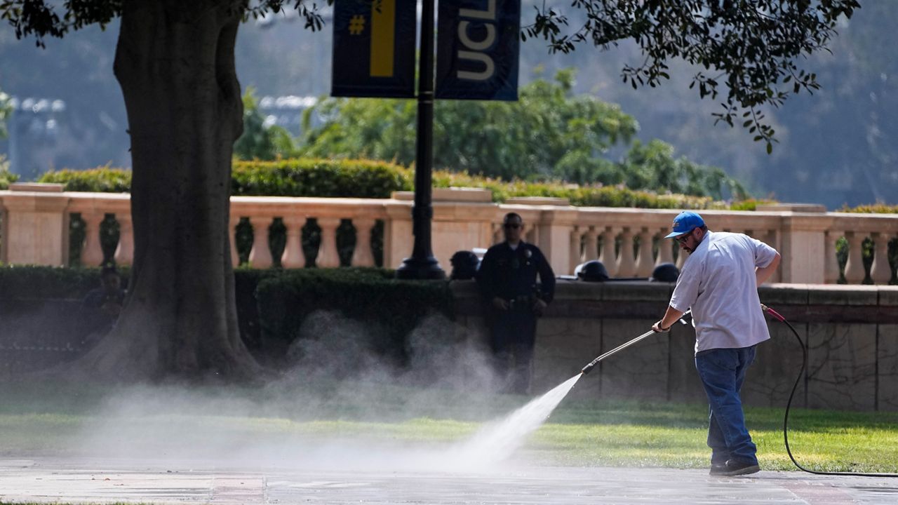 A man power washes the ground as the cleanup continues on the site of a pro-Palestinian encampment, cleared by police overnight, on the UCLA camp on May 2, 2024, in Los Angeles. (AP Photo/Mark J. Terrill)