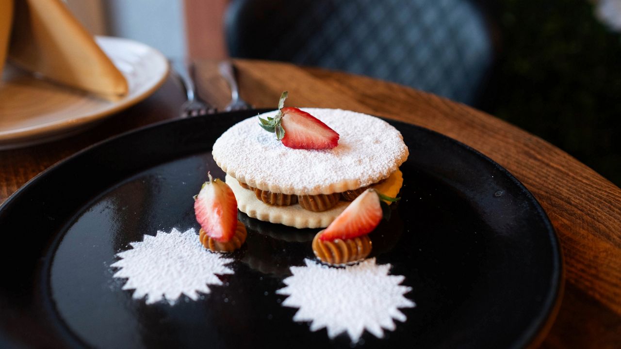 Peruvian dessert arranged on a black plate, sitting on a dark wooden table